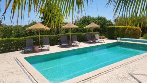 a swimming pool with chairs and umbrellas at Casa Aventura in Boliqueime