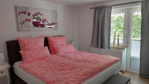 a bedroom with a bed with pink sheets and a window at Haus Emmerblick in Schieder-Schwalenberg
