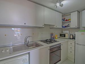 kuchnia z białymi szafkami, zlewem i lodówką w obiekcie Apartment Apolo VII-9 by Interhome w mieście Calpe