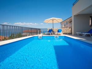 a swimming pool with two chairs and an umbrella at Holiday Home Villa Vali 2 by Interhome in Vrbnik