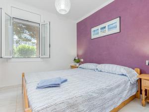 a bedroom with a bed and a purple wall at Apartment Flamicell by Interhome in Empuriabrava
