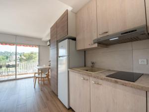 kuchnia z drewnianymi szafkami i dużym oknem w obiekcie Studio Les Pradels by Interhome w mieście Cavalaire-sur-Mer