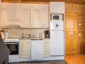 a kitchen with white appliances and wooden cabinets at Holiday Home Saana 1 by Interhome in Kilpisjärvi