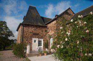 una casa de piedra con techo negro en Manoir La Haie Chapeau, en Saint-Thurial