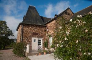 a stone house with a black roof at Manoir La Haie Chapeau in Saint-Thurial