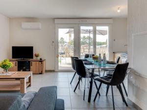 a living room with a table and chairs and a television at Apartment Soleil Couchant B03 by Interhome in Mimizan