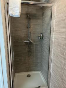 La salle de bains est pourvue d'une douche avec une porte en verre. dans l'établissement Weslie Guest House, à Brighton et Hove