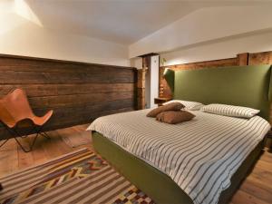 a bedroom with a bed with a green headboard and a chair at Chalet Baita Barin by Interhome in Madesimo