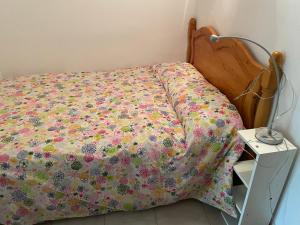 uma cama com uma colcha floral com uma mesa de cabeceira em Sol i Neu em Encamp