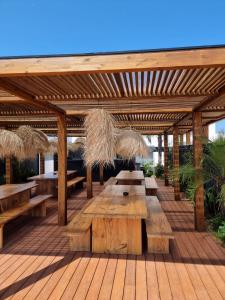 a wooden pergola with wooden tables and benches at The Salty Pelican Yoga & Surf Retreat in Peniche +27 photos