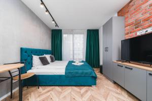 a bedroom with a blue bed and a flat screen tv at Ice Apartments in Kraków