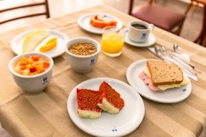 a table with plates of food and cups of orange juice at Hotel Dan Inn Araraquara in Araraquara