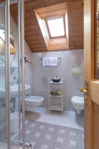 uma casa de banho com um lavatório, um WC e uma janela. em Ciasa Rü em San Cassiano