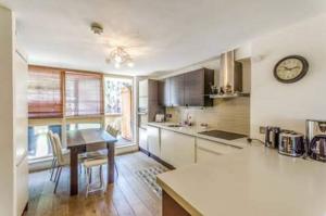 uma cozinha com uma mesa e um relógio na parede em Super Central beautiful 3 Bedroom em Londres