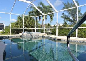 - une piscine d'eau bleue avec des palmiers dans l'établissement SUNNY MORNINGS * 4 bed/2.5 bath * gulf access *, à Cape Coral