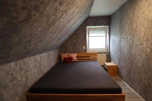 ein kleines Schlafzimmer mit einem Bett und einem Fenster in der Unterkunft Haus Flieder in Krummhörn