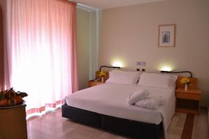 a bedroom with a white bed with two towels on it at Hotel Pomara in San Michele di Ganzaria