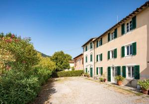 een onverharde weg naast een gebouw met groene luiken bij La Dimora di Corte a Lucca in Lucca