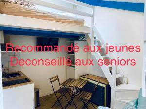 Cette chambre comprend des lits superposés, une table et des chaises. dans l'établissement ECO STUDIOS mezzanine wifi piscine stationnement gratuit terrasse dans jardin, à Rouen