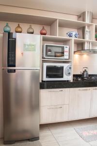 a kitchen with a stainless steel refrigerator and microwave at Casa Petri Gramado casa inteira para 7 pessoas ideal para famílias in Gramado