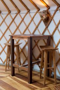 a wooden table and two stools in a room at Yourte La Désirade in Semur-en-Auxois