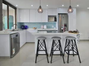 a kitchen with white cabinets and two bar stools at Simla Luxury Apartments in Margate