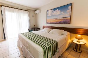 1 dormitorio con cama y ventana grande en Resort Costa Dos Coqueiros, en Imbassai