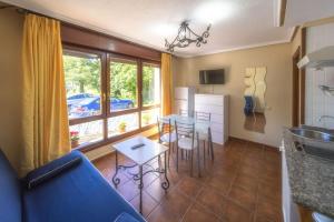 a kitchen and living room with a blue couch and a table at Apartamentos Trébede in Barro de Llanes