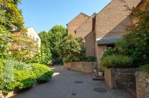 an alley in a brick building with bushes and trees at Veeve - Float Your Boat in London