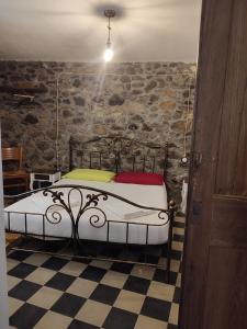 a bedroom with a bed in a stone wall at Deiana in Santu Lussurgiu