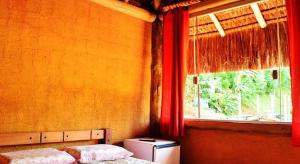 a bedroom with two beds and a window with red curtains at Pousada Bangalô de Barro in Paraty