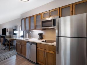 a kitchen with a stainless steel refrigerator and wooden cabinets at Staybridge Suites - Sioux City Southeast, an IHG Hotel in Sioux City