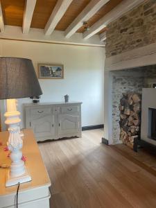 a living room with a fireplace and a table with a lamp at Cottage Philmaries in Coudert