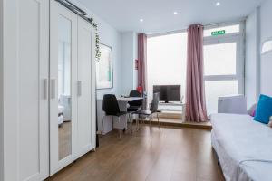 Jest to biały pokój z łóżkiem, biurkiem i stołem. w obiekcie ApartEasy - Goya Ground Floor Studio w Madrycie +12 zdjęć