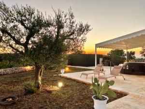 a patio with two chairs and a tree in a yard at EnjoyTrulli - Countryside in Noci