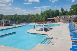 ein großer Swimmingpool mit blauen Stühlen drumherum in der Unterkunft Golf, Ski and Fish Cabin with Deck in Tobyhanna! in Tobyhanna