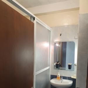 a bathroom with a sink and a shower with a mirror at Suit Home in Martil