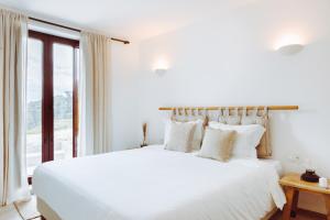 een witte slaapkamer met een groot bed en een raam bij Oliveiras Village — Agroturismo in Amarante