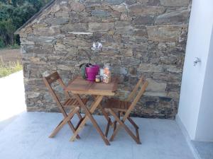 uma mesa de madeira e duas cadeiras em frente a uma parede de pedra em Appartement vue sur mer em Santa-Maria-di-Lota