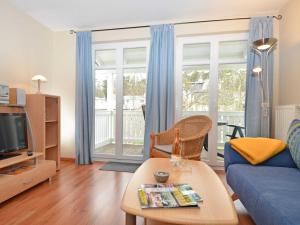a living room with a blue couch and a tv at Villa Seerose - Appartement 18 in Ostseebad Sellin