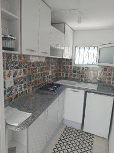 a small kitchen with white cabinets and tiles on the wall at Dar Fatma in Hammamet