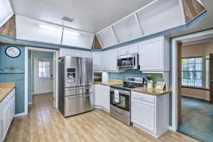 uma cozinha com armários brancos e um frigorífico de aço inoxidável em Titusville Vacation Rental Home Near Parks and Golf! em Titusville