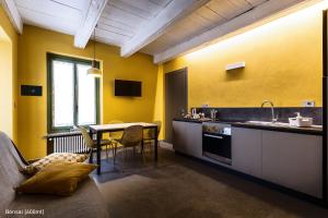 eine Küche mit gelben Wänden, einem Tisch und einem Waschbecken in der Unterkunft San Francesco Guest House in Savigliano