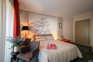 ein Schlafzimmer mit einem Bett, einem Stuhl und einem Gemälde in der Unterkunft San Francesco Guest House in Savigliano