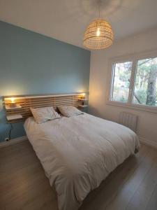 Un dormitorio con una gran cama blanca y una ventana en maison landaise à proximité de la plage et centre en Biscarrosse-Plage
