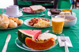 una mesa verde cubierta con platos de comida y bebida en Pousada Guarubela Veloso, en Ilhabela