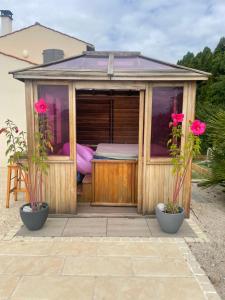 a wooden house with a bed in it with two plants at Piscine ET JACUZZI ST GEORGES DE DIDONNE a 1km de la plage in Saint-Georges-de-Didonne