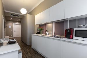 uma cozinha com armários brancos e um micro-ondas em Studio Inn De Angeli em Milão