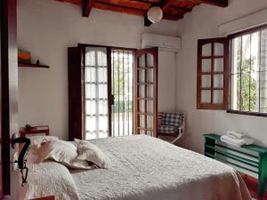 Un dormitorio con una cama con sábanas blancas y ventanas. en Casa de las Palmeras, en Yerba Buena
