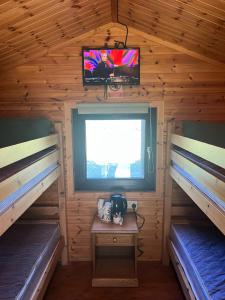 una camera con due letti e una TV in una baita di tronchi di MacDonald Cabins a Kinlochleven